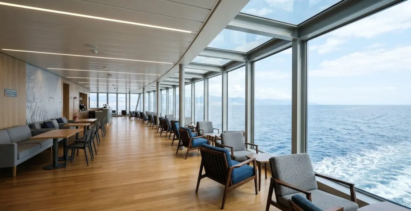 Ampia area lounge di un traghetto moderno con grandi vetrate che affacciano sul mare aperto, design contemporaneo luminoso